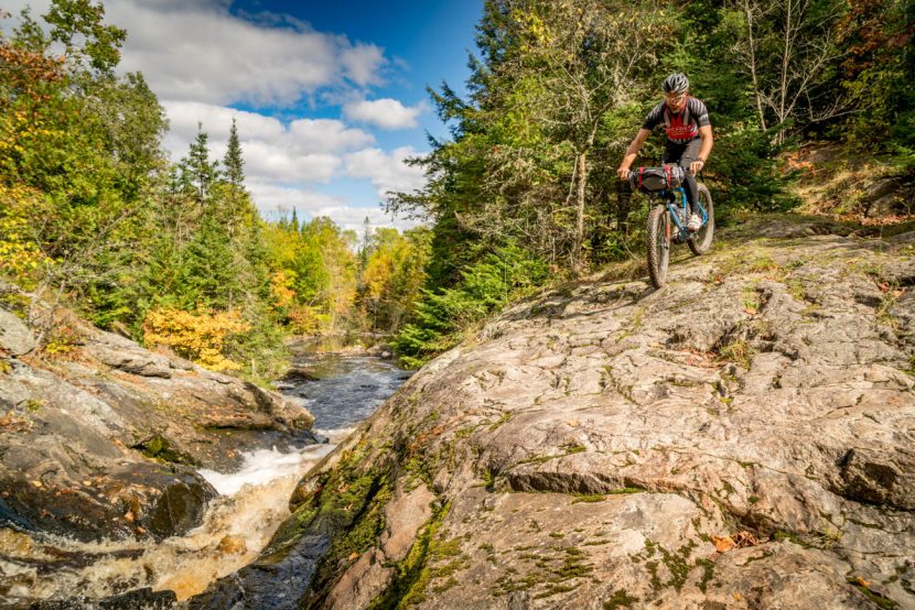 Bike rider on rocks next to waterfall