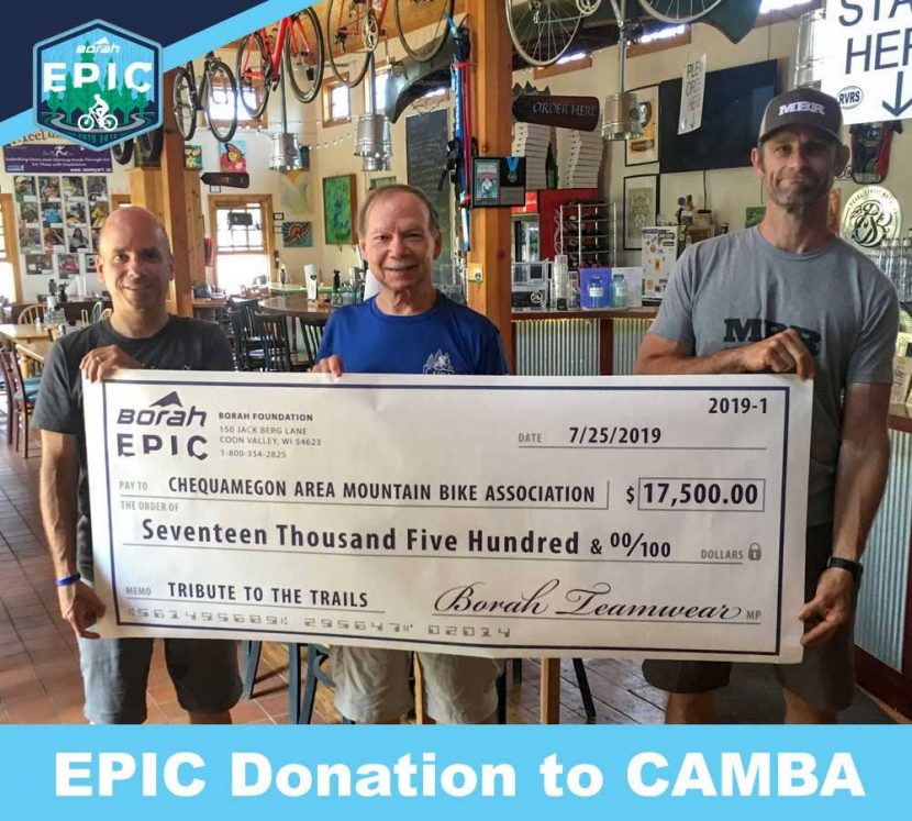 Three people hold giant check from Borah Epic to CAMBA for $17,500