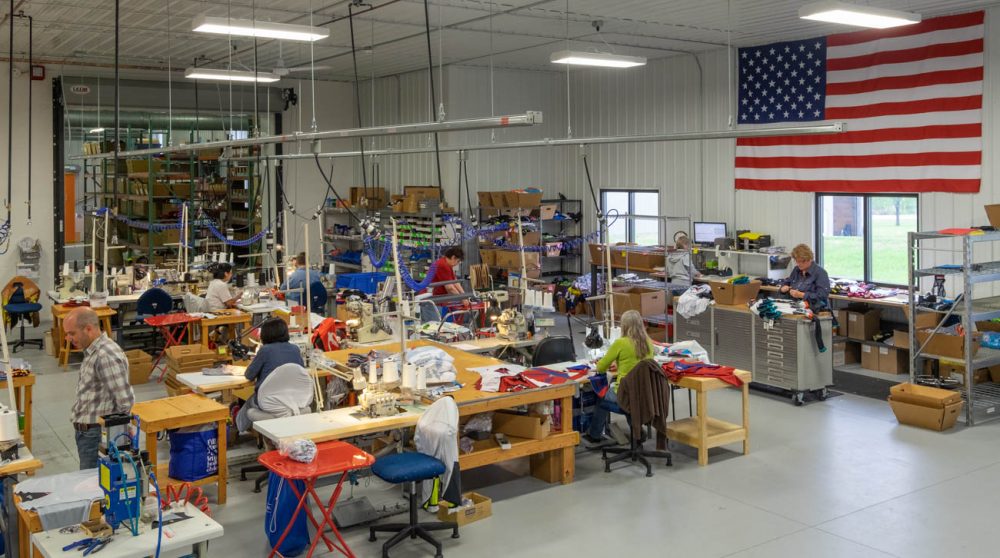 Sewing room at Borah Teamwear with large American flag on wall.