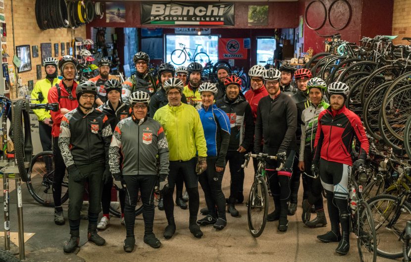 Cyclists stand inside bike shop before ride