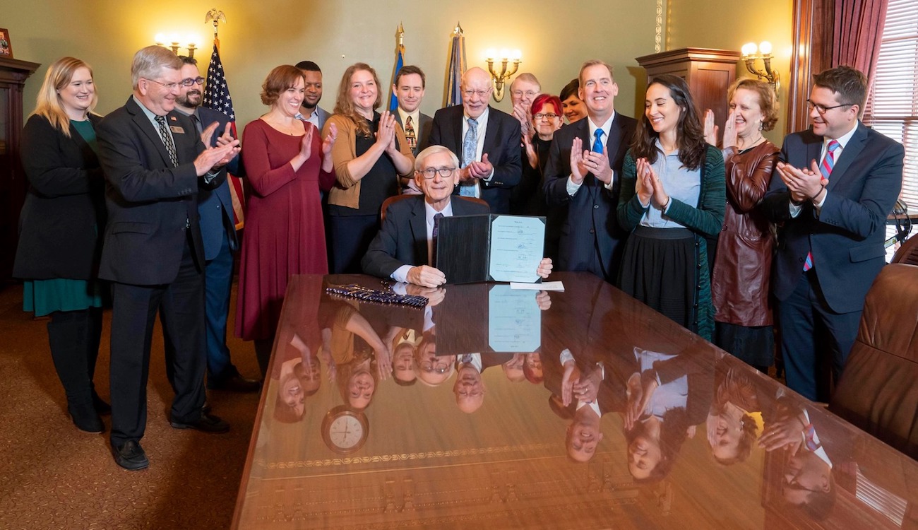 Governor Evers surrounded by clapping people after signing e-bike legislation