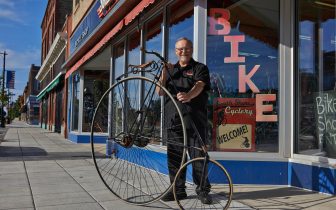 South Shore Cyclery co-owner Scott Nicholes holds an antique penny farthing in front of his shop.