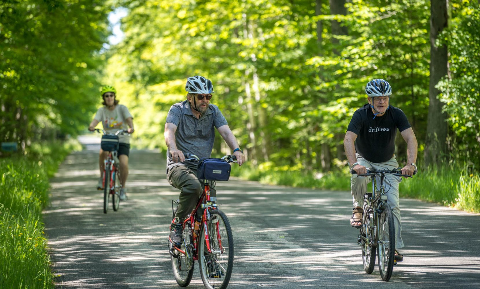 Three people ride bikes on a pretty road on Washington Island.