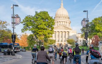 A group of people riding bicycles in front of the Wisconsin State Capital Building
