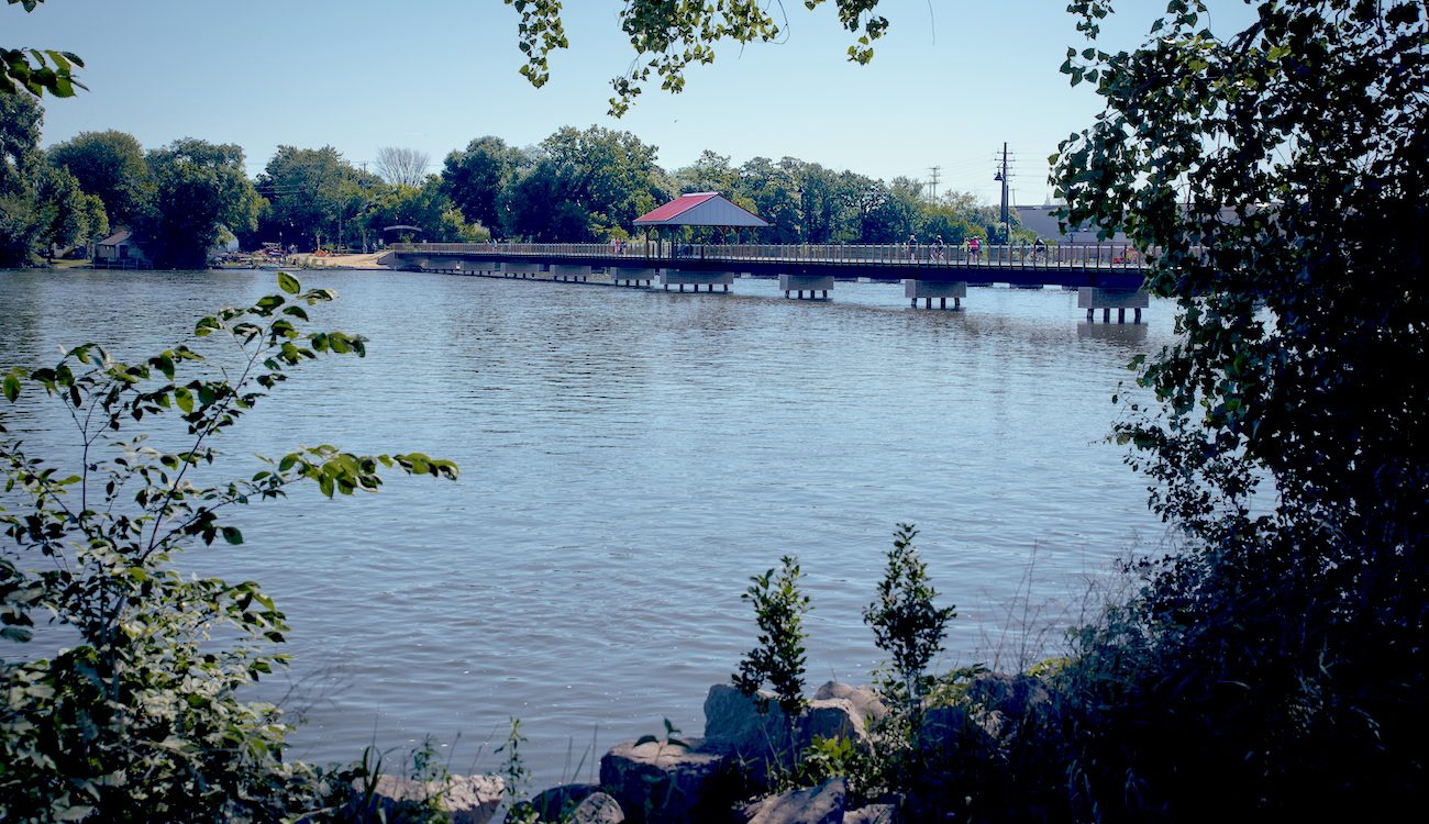 Fox River and trestle bike bridge with bushes in foreground
