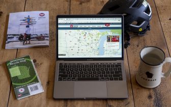 Photo of laptop open to this website with magazine, map, helmet and mug next to it