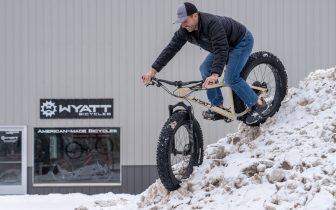 Wyatt Hrudka rides a fat bike down a snow pile in front of his business, Wyatt Bicycles