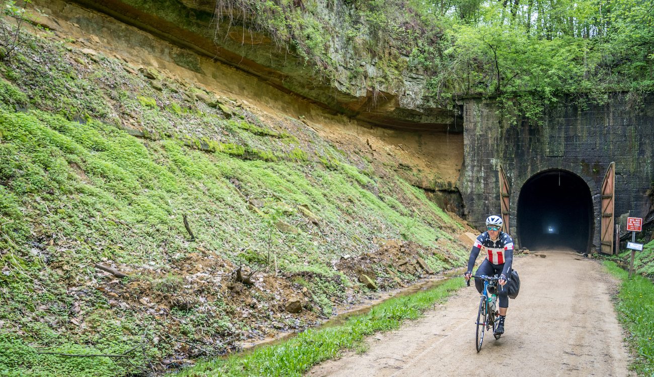 man rides bicycle out of tunnel on Elroy Sparta trail