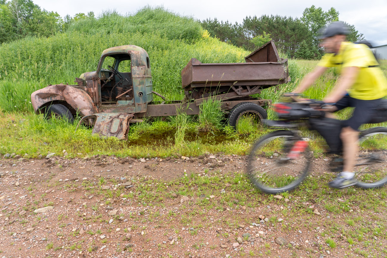 a person on a bike rides past an old truck