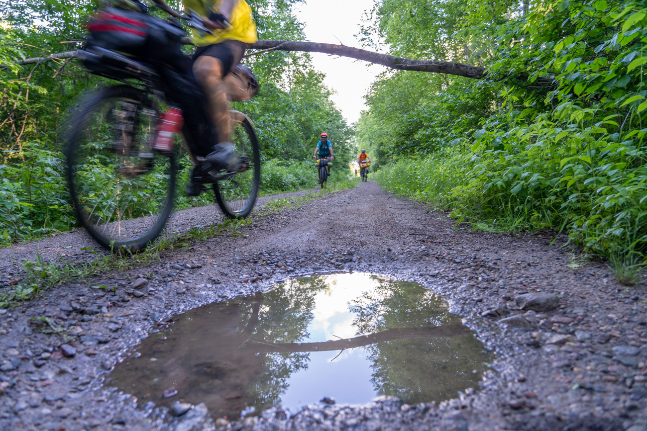 riding past a puddle on a gravel road