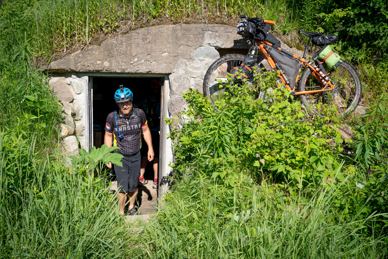 Man wearing helmet walks up stairs from underground bunker next to bicycle