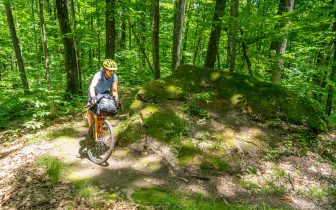 Woman rides past a boulder in the forest