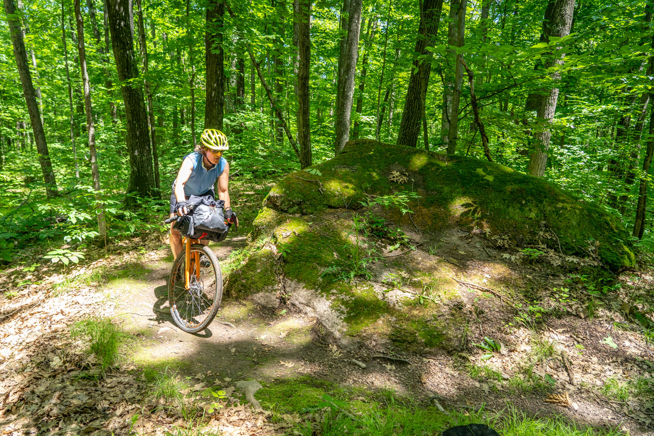 Woman rides past a boulder in the forest
