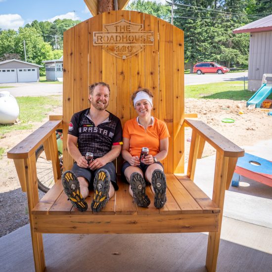 Husband and wife sit in an oversized wooden chair