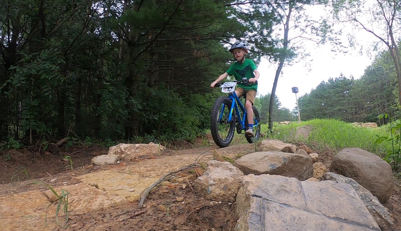 young kid rides over dirt and rocks on bike