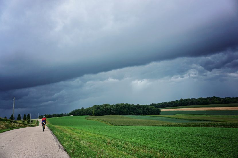 Laura rides down the road as a large dark storm forms ahead.