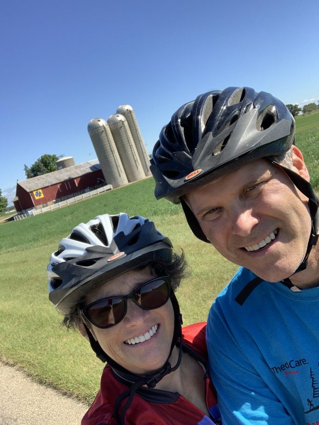 Two cyclists take a selfie with a red barn in the background
