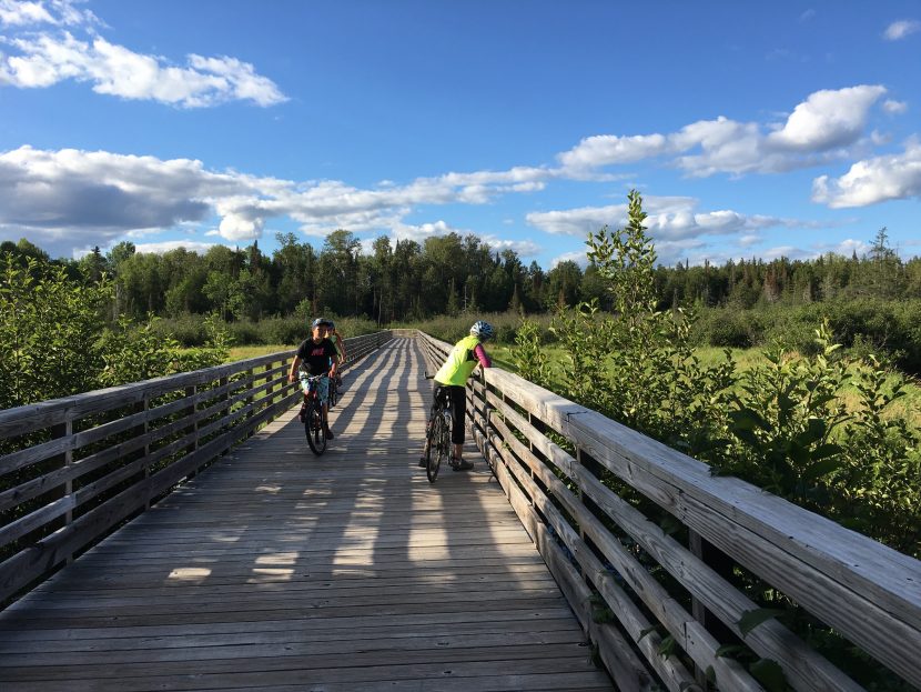 Young riders look over the edge of a boardwalk on the trail.