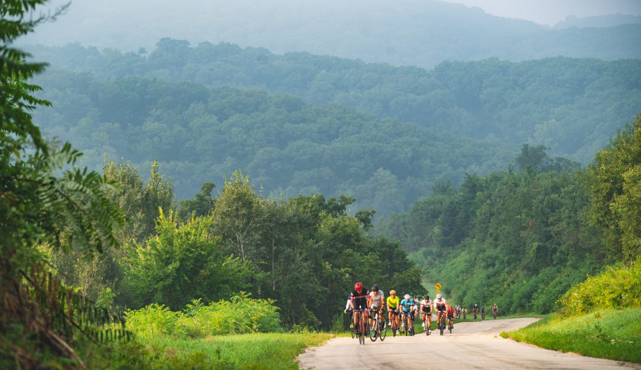 Cyclists riding on rural road with rolling hills in the background