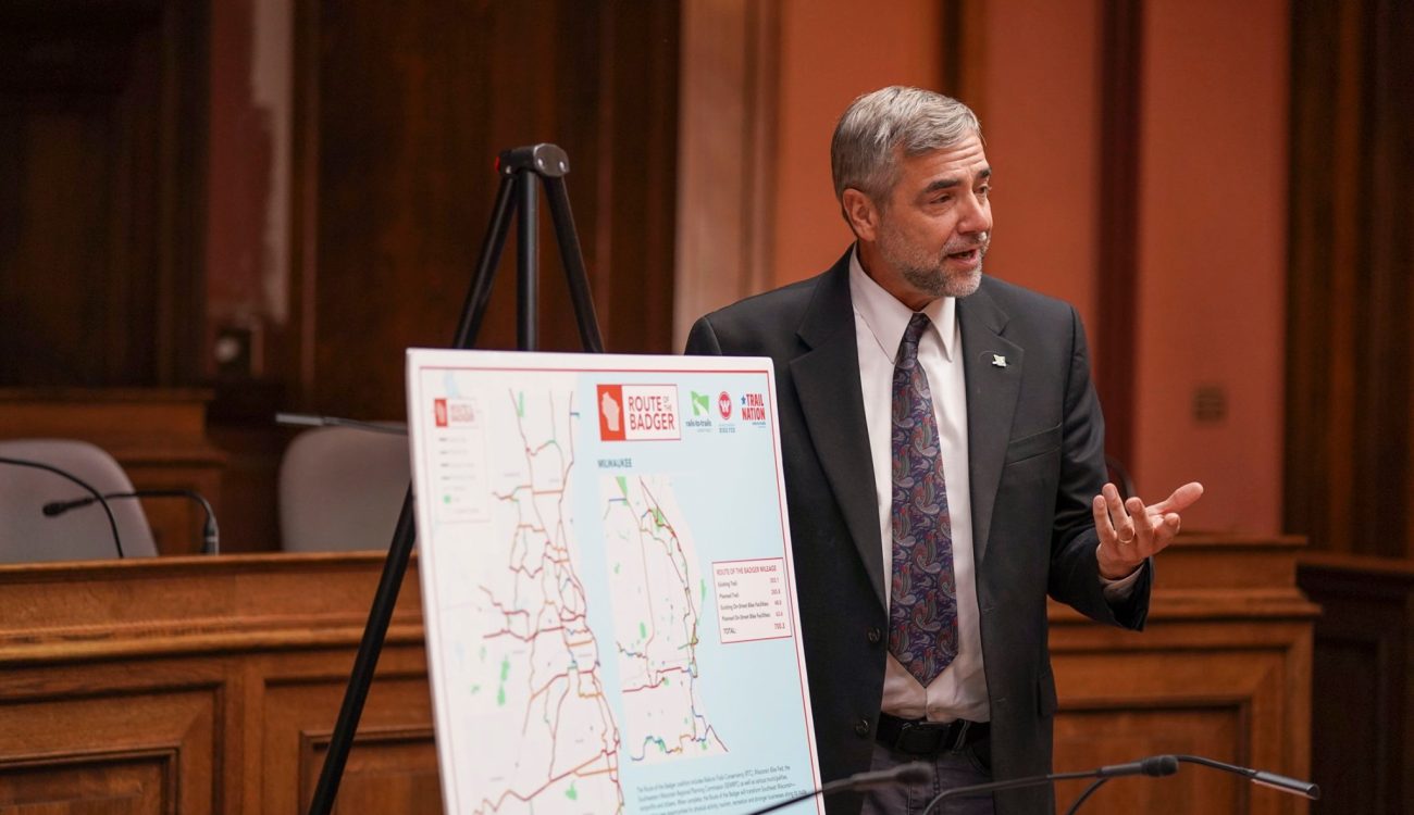 Willie Karidis speaking beside easel with enlarged route map