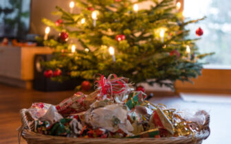 basket of wrapping paper and ribbons in foreground with Christmas tree in background