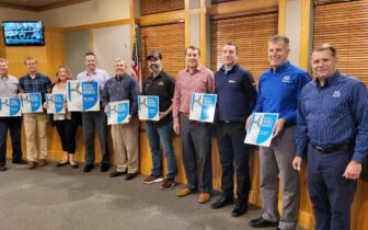 Ten Fitchburg Wisconsin businesses holding their League of American Bicyclists Bicycle Friendly Business award signs