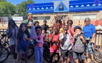 children and adult instructor eating popsicles on a hot day at a outdoor dining parklet after riding their bikes there
