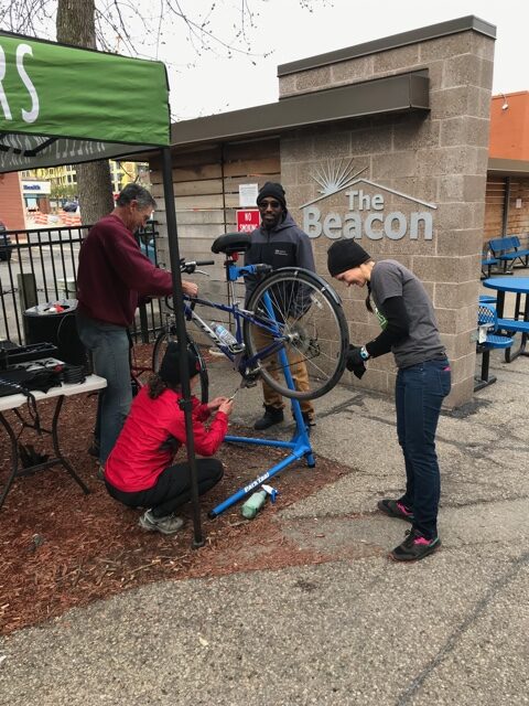 mechanics help fix bikes outside of the Beacon an organization that helps houseless people