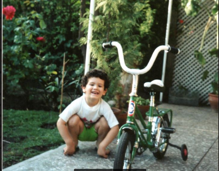 Young Pepe squatting next to his two-wheeler