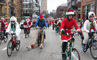 thousands of costumed riders pedal with smile on faces on an urban street