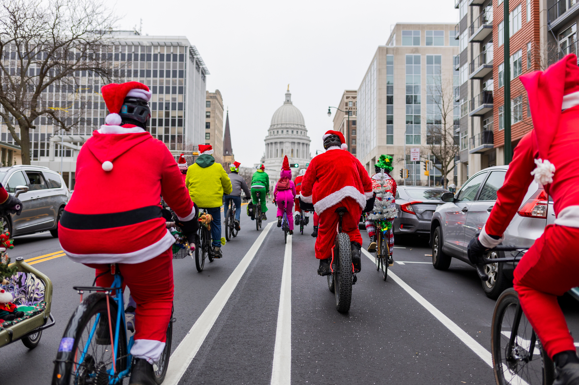 a view from behind of several bike riders in holiday and Santa costumes riding towards the capitol building in Madison