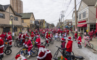 hundreds of bike riders in holiday costumes fill a city street