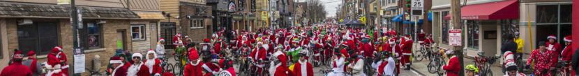 hundreds of bike riders in holiday costumes fill a city street