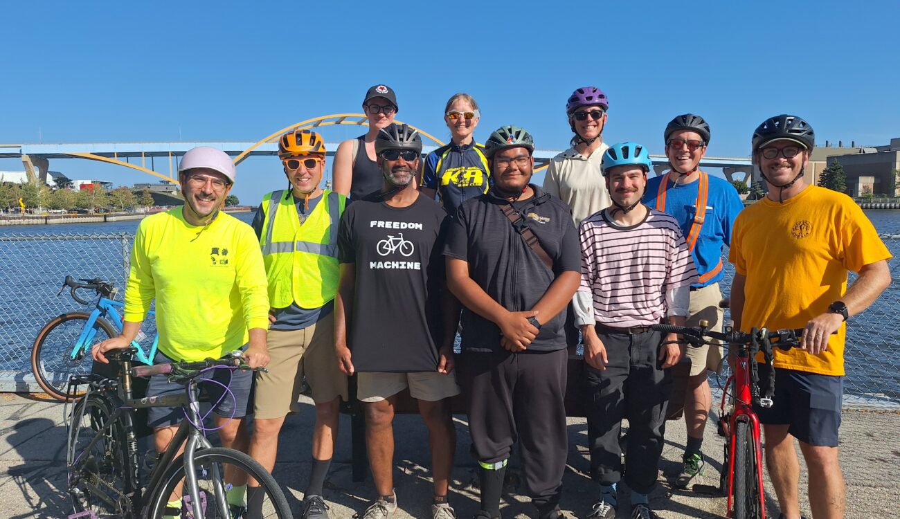 a group of people stand next to the rider and under the hoan bridge smiling and posing for the photo